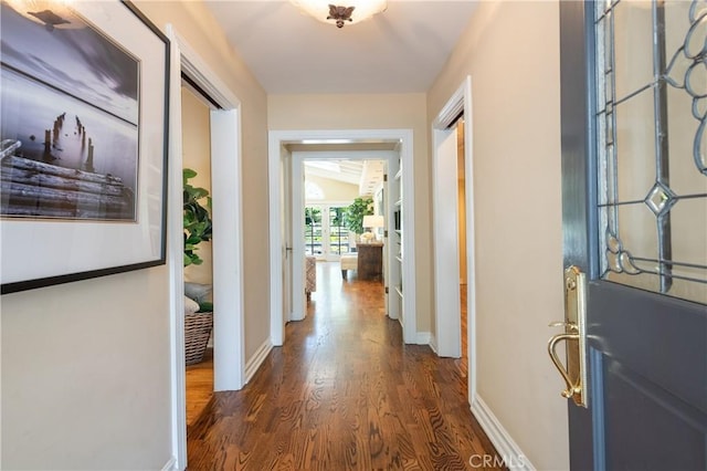 corridor featuring baseboards and dark wood finished floors
