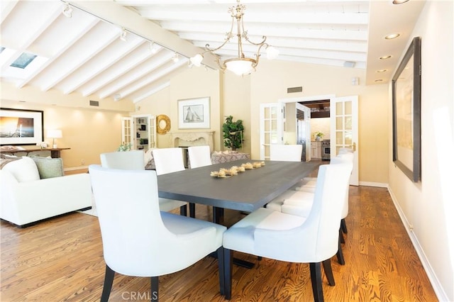 dining space with baseboards, rail lighting, french doors, vaulted ceiling with beams, and wood finished floors