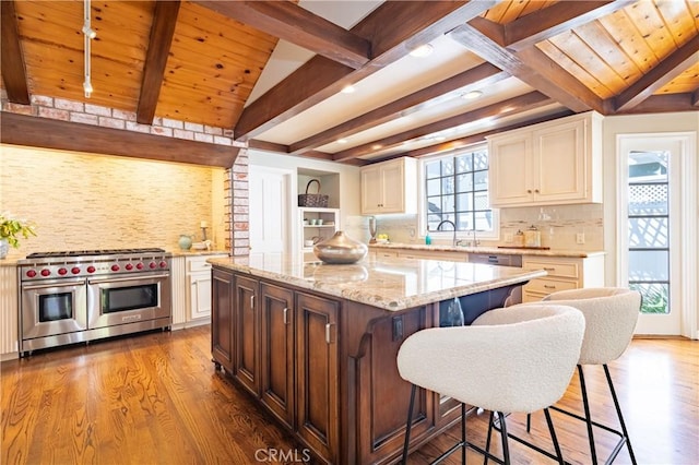 kitchen with wooden ceiling, double oven range, wood finished floors, light stone countertops, and decorative backsplash