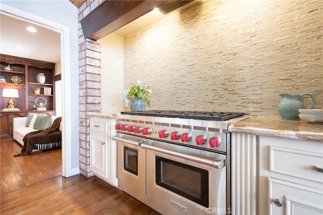 kitchen featuring white cabinets, double oven range, light stone counters, dark wood-style flooring, and decorative backsplash