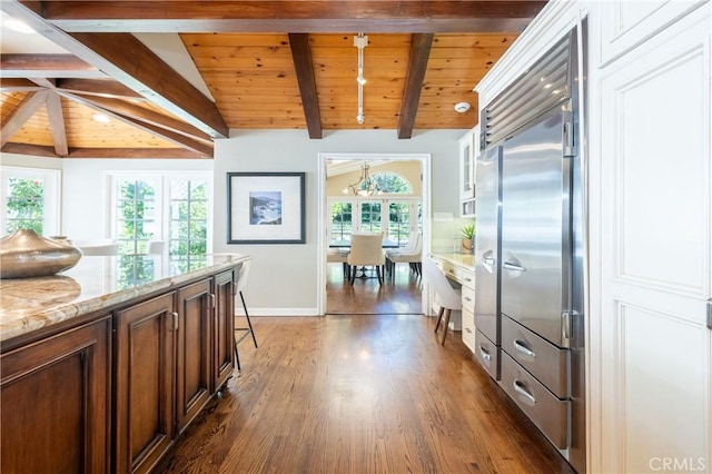 corridor featuring baseboards, an inviting chandelier, lofted ceiling with beams, dark wood-style flooring, and wood ceiling