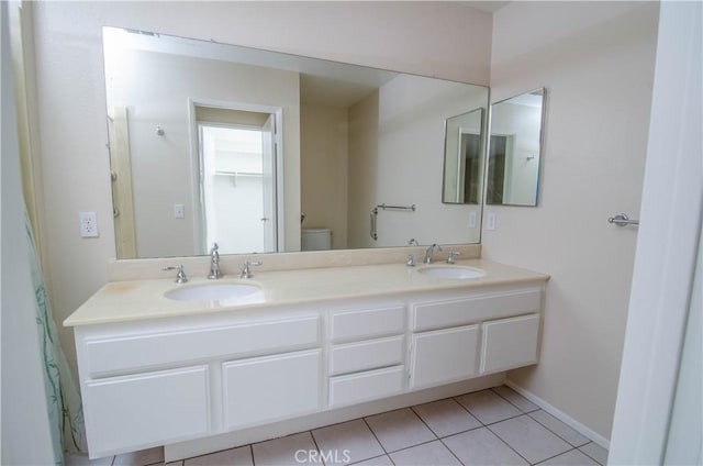 bathroom with toilet, double vanity, a sink, and tile patterned floors