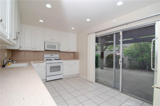 kitchen featuring a sink, light tile patterned flooring, white appliances, light countertops, and white cabinets