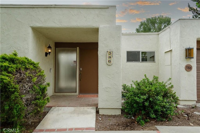 doorway to property featuring stucco siding
