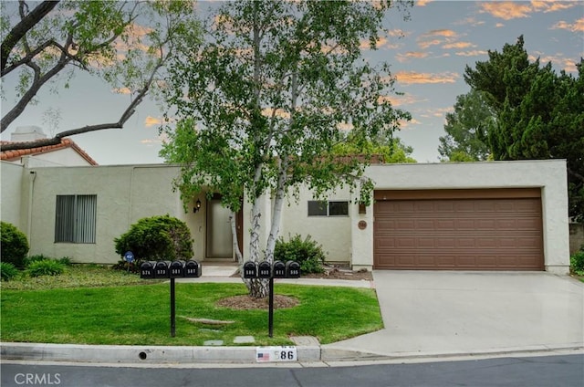 view of front of house featuring a yard, stucco siding, concrete driveway, and an attached garage