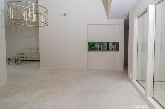 carpeted empty room featuring visible vents and a notable chandelier