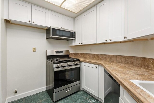 1044 Calle Del Cerro Unit 301, San Clemente, CA 92672 - kitchen with dark tile patterned floors, white cabinets, and stainless steel appliances