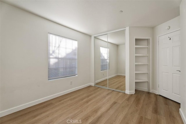 1044 Calle Del Cerro Unit 301, San Clemente, CA 92672 - unfurnished bedroom featuring baseboards, light wood-style floors, and a closet