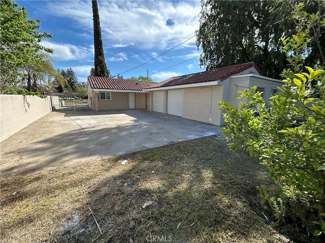garage with fence, a gate, and driveway