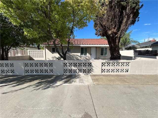 mediterranean / spanish-style house featuring a tiled roof, fence, and stucco siding