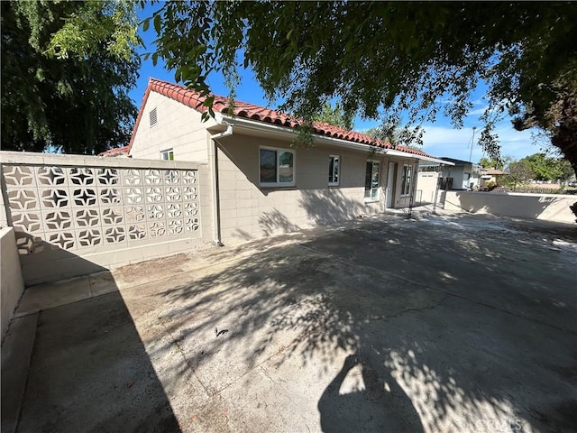 back of property with concrete block siding and a tiled roof