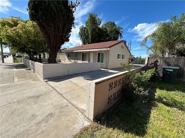 back of house with a tiled roof, a fenced front yard, and stucco siding