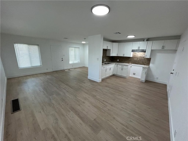kitchen featuring open floor plan, baseboards, visible vents, and a sink