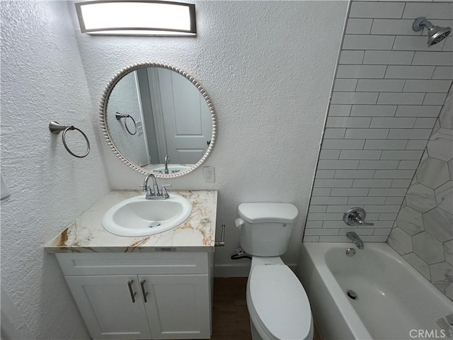 bathroom featuring toilet, shower / bathing tub combination, vanity, and a textured wall
