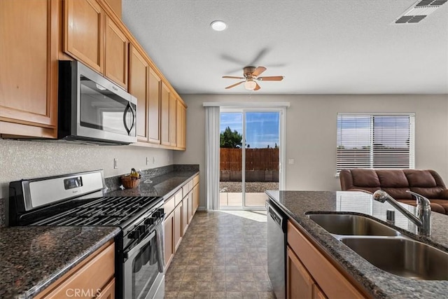 930 Travertine Way, Atwater, CA 95301 - kitchen featuring dark stone countertops, a ceiling fan, visible vents, appliances with stainless steel finishes, and a sink