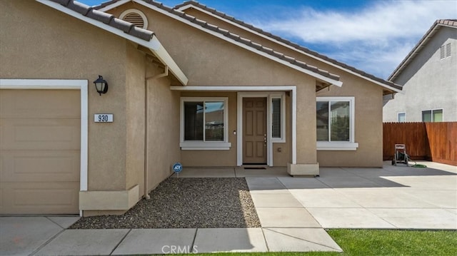 930 Travertine Way, Atwater, CA 95301 - entrance to property with stucco siding, fence, a tiled roof, and a garage