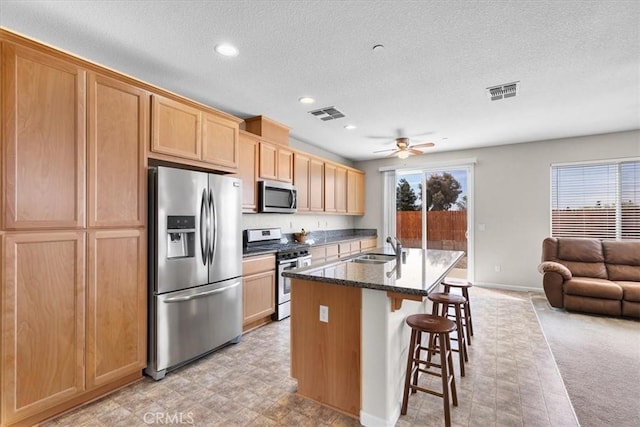930 Travertine Way, Atwater, CA 95301 - kitchen featuring visible vents, a sink, ceiling fan, appliances with stainless steel finishes, and a kitchen breakfast bar
