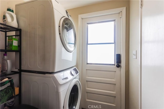 laundry area featuring stacked washer and clothes dryer, laundry area, and a healthy amount of sunlight