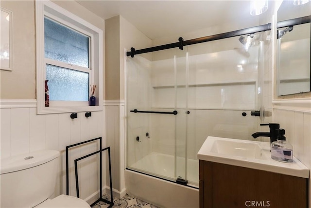 full bath featuring enclosed tub / shower combo, wainscoting, toilet, and vanity