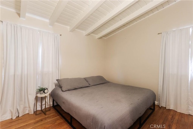 bedroom with lofted ceiling with beams and wood finished floors