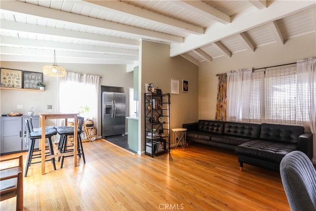 living area with vaulted ceiling with beams and light wood-style flooring