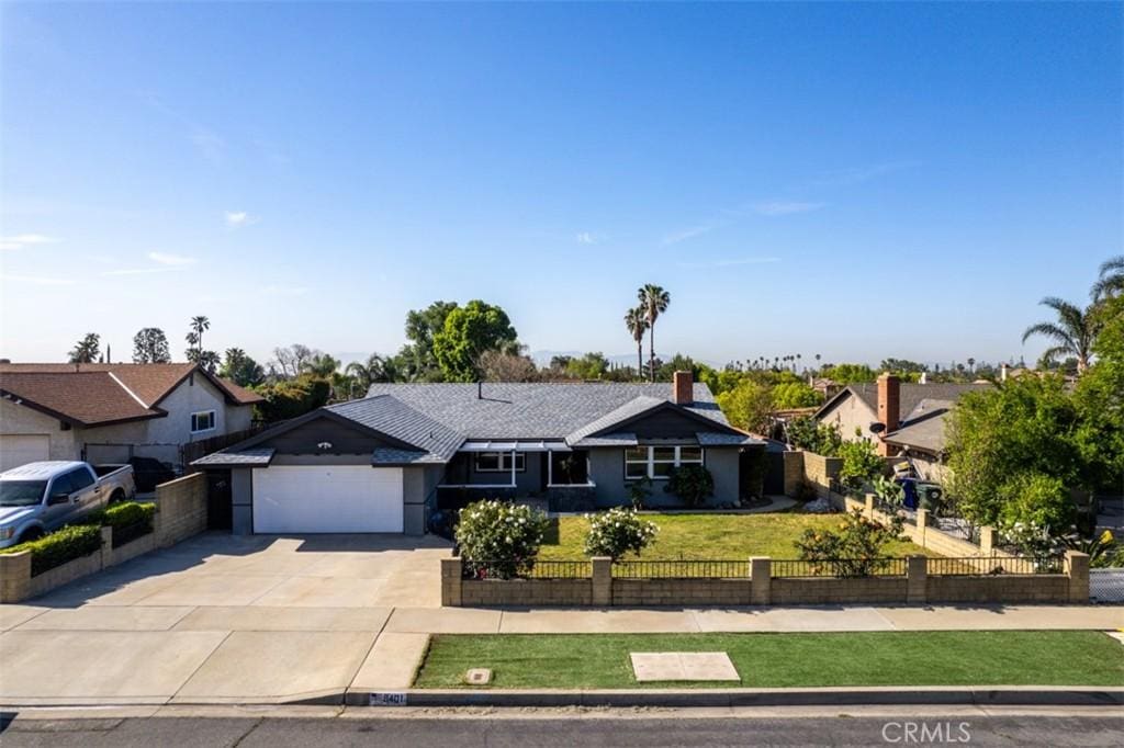 ranch-style home with an attached garage, a front lawn, driveway, and a fenced front yard