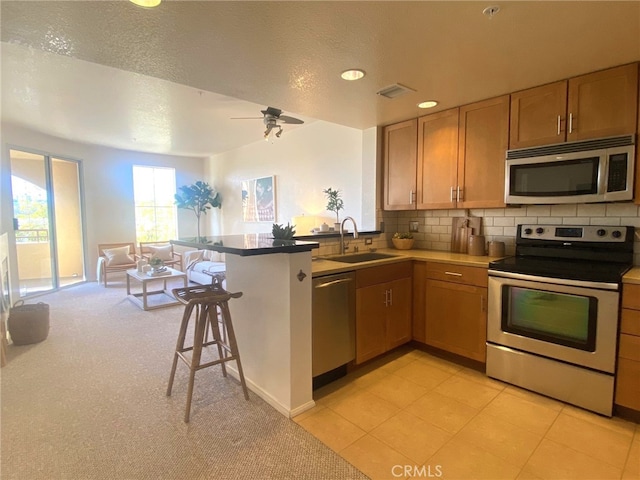 kitchen with a kitchen breakfast bar, a peninsula, visible vents, a sink, and stainless steel appliances