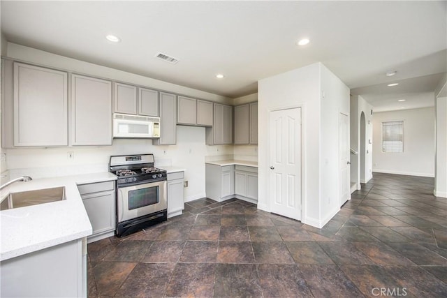 11834 Greenbluff Way, Yucaipa, CA 92399 - kitchen featuring stainless steel gas range oven, white microwave, a sink, gray cabinetry, and baseboards