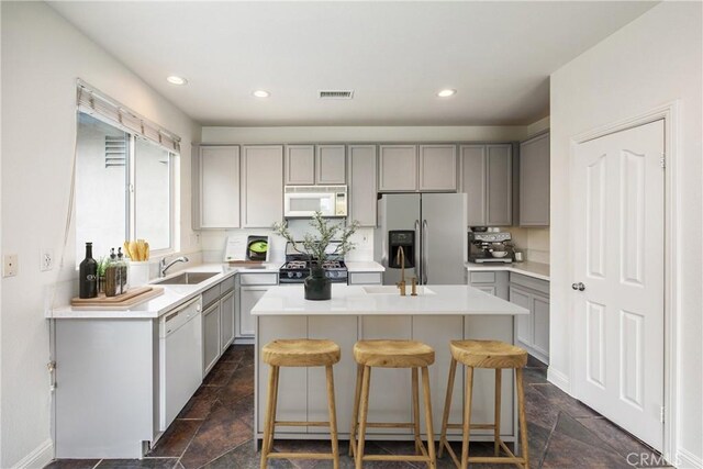 11834 Greenbluff Way, Yucaipa, CA 92399 - kitchen with white appliances, gray cabinets, stone tile flooring, a center island, and a kitchen bar