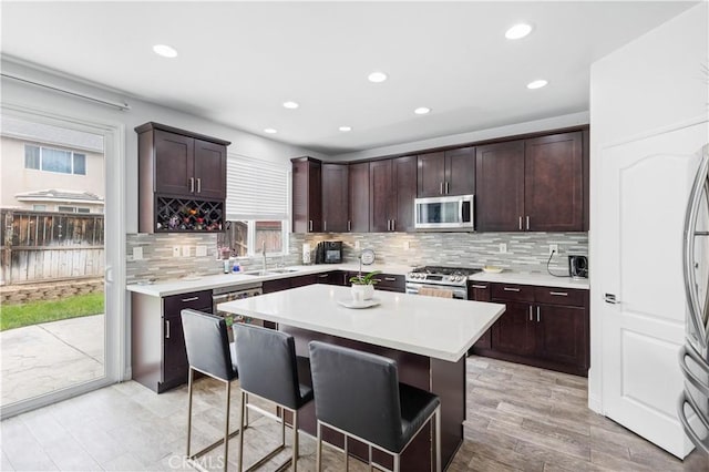 kitchen with light countertops, appliances with stainless steel finishes, a breakfast bar, recessed lighting, and backsplash