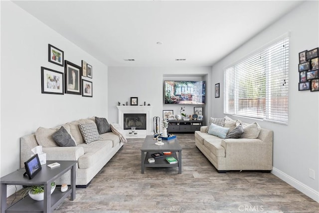 living room with visible vents, baseboards, plenty of natural light, and wood finished floors
