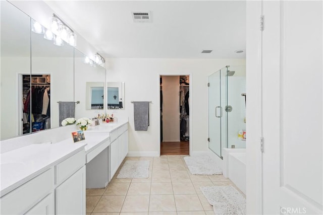 bathroom with double vanity, tile patterned flooring, a shower stall, a walk in closet, and visible vents