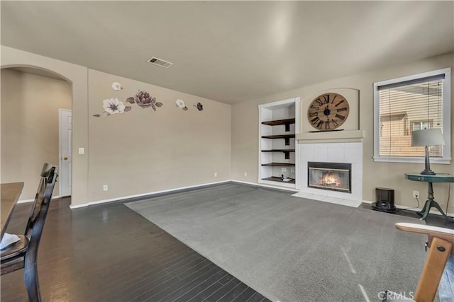 4022 Cocina Ln, Palmdale, CA 93551 - unfurnished living room featuring dark wood-style floors, arched walkways, visible vents, baseboards, and built in shelves