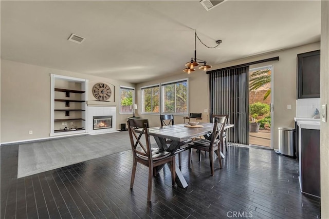4022 Cocina Ln, Palmdale, CA 93551 - dining area featuring a tiled fireplace, dark wood-type flooring, visible vents, and built in shelves