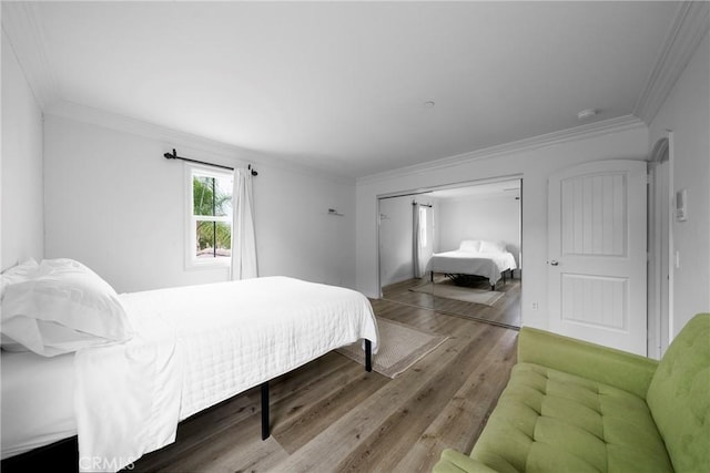 bedroom with ornamental molding, wood finished floors, and a closet