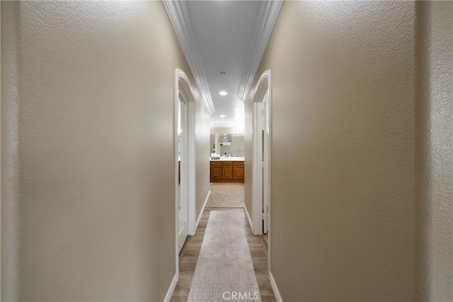 hallway with recessed lighting, light wood-style flooring, crown molding, and baseboards