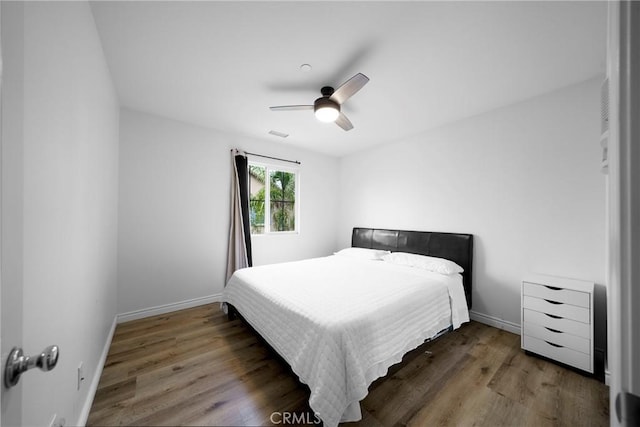 bedroom featuring baseboards, a ceiling fan, wood finished floors, and visible vents