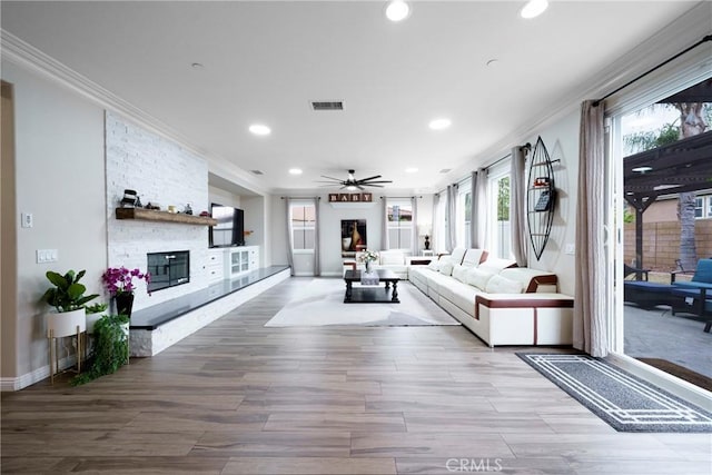 living area with crown molding, visible vents, and a fireplace