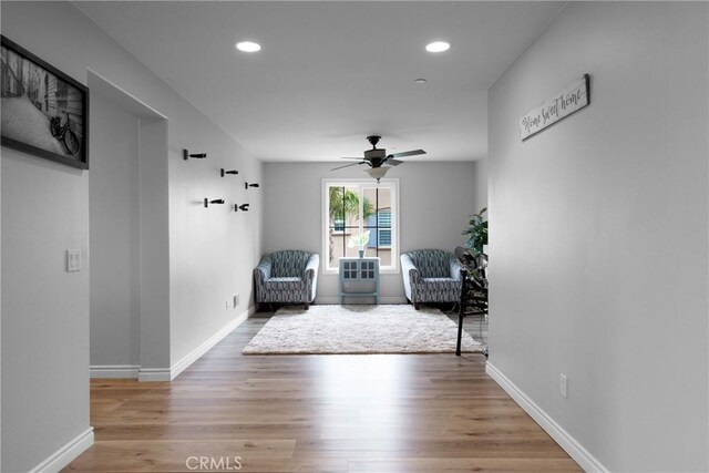 living area with baseboards, a ceiling fan, light wood-style floors, and recessed lighting