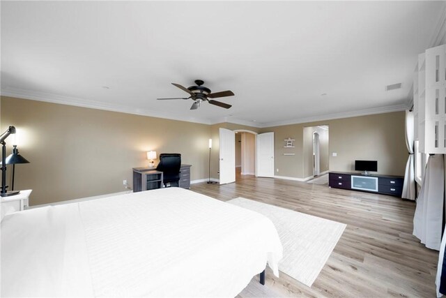 bedroom featuring light wood-style floors, ceiling fan, arched walkways, baseboards, and ornamental molding