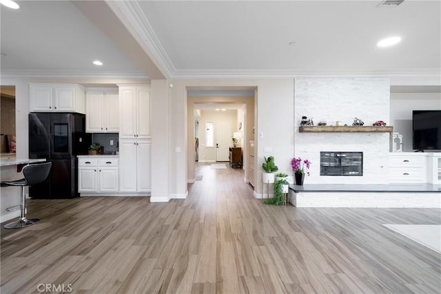 kitchen featuring white cabinets, freestanding refrigerator, light wood-type flooring, crown molding, and decorative backsplash