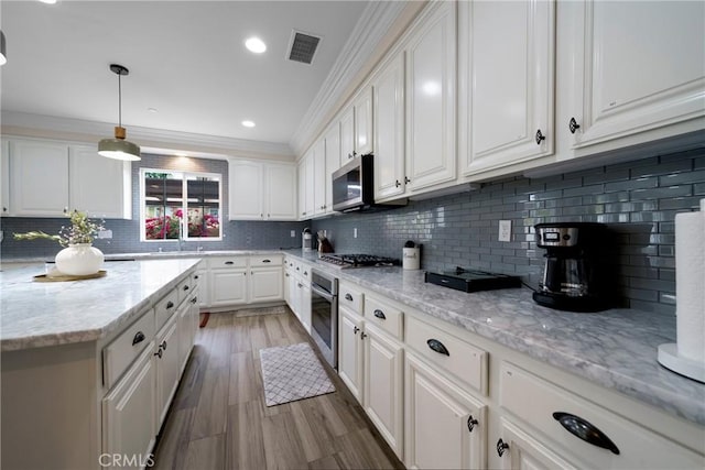 kitchen with stainless steel appliances, visible vents, crown molding, decorative backsplash, and white cabinetry