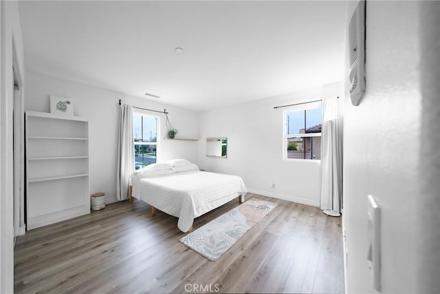 bedroom with visible vents, baseboards, and wood finished floors