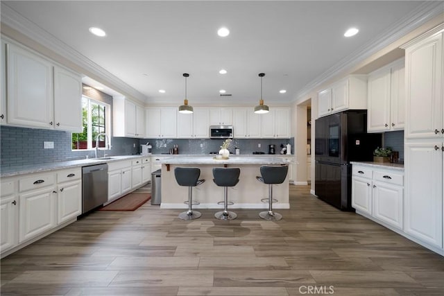 kitchen featuring a breakfast bar, appliances with stainless steel finishes, light countertops, backsplash, and white cabinetry