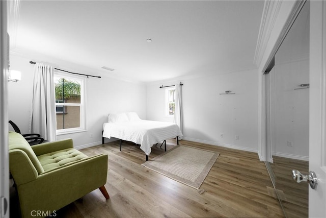 bedroom with wood finished floors, baseboards, and multiple windows
