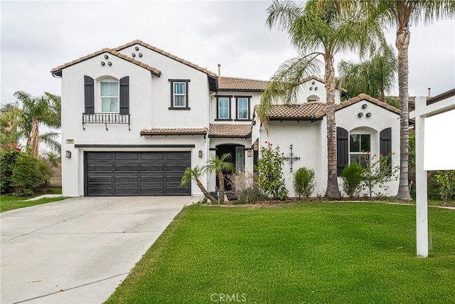 mediterranean / spanish house with concrete driveway, a tiled roof, an attached garage, a front yard, and stucco siding