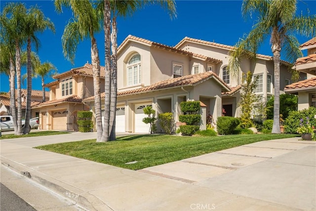 mediterranean / spanish house with stucco siding, a front yard, a tile roof, a garage, and concrete driveway