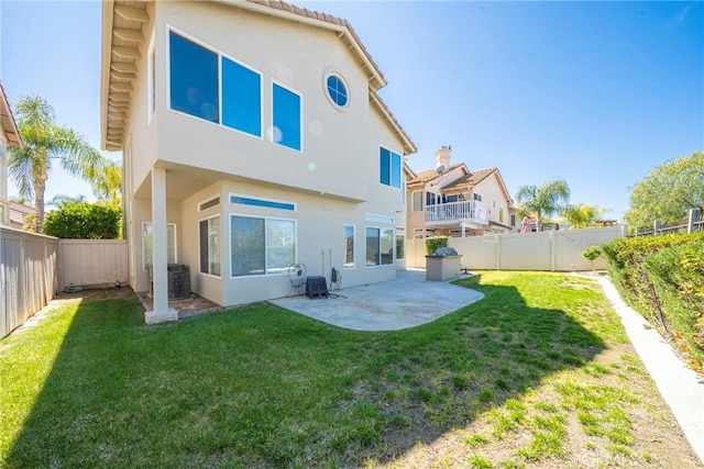 back of house with a yard, a fenced backyard, stucco siding, and a patio area