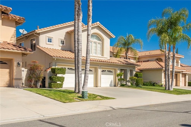 mediterranean / spanish house featuring an attached garage, a tiled roof, driveway, and stucco siding