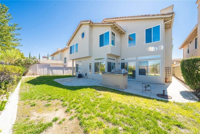 rear view of house with a patio area, a fenced backyard, a yard, and stucco siding